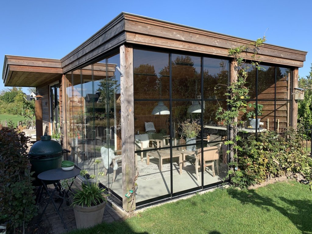 Terrasoverkapping met glazen schuifwanden Sittard - Geleen Limburg. Moderne houten overkapping met glazen schuifwanden, sfeervolle inrichting met tuinmeubelen.