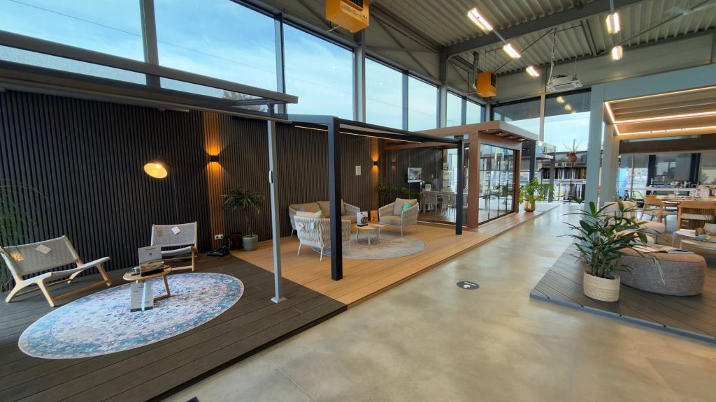 Patio covers with lounge areas along the glass fa&ccedil;ade of the Renoco showroom in Sittard.
