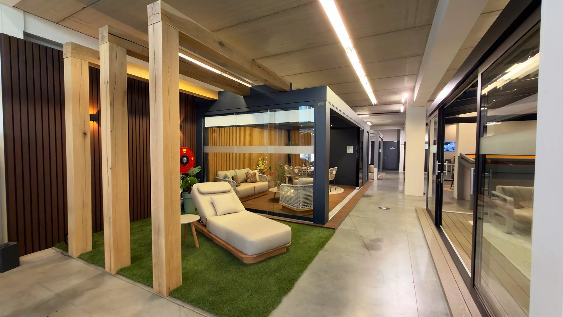 Garden room with sliding glass walls, a lounge set and a daybed in the Renoco showroom