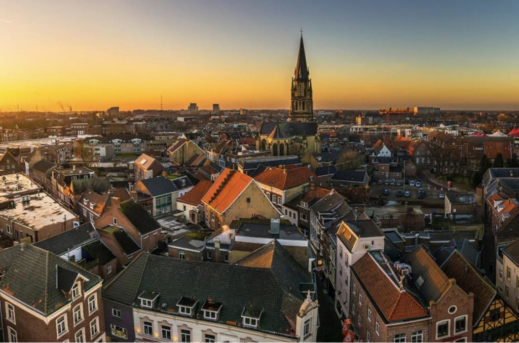 Panoramisch uitzicht op het centrum van Sittard met de kerktoren en historische gebouwen bij zonsondergang.