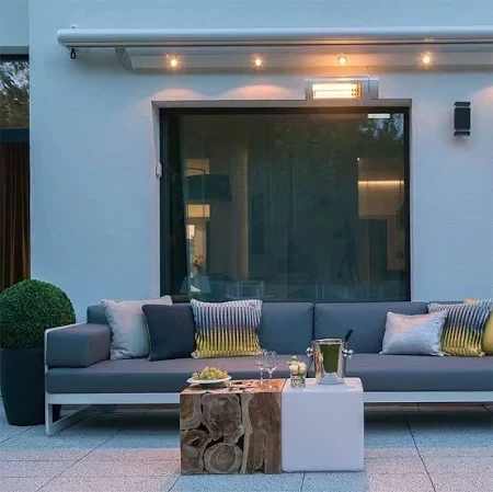 Verhoog uw comfort met deze design terrasverwarmer Design terrasverwarmer geïnstalleerd boven een moderne zithoek op een patio, met sfeerverlichting en stijlvolle meubels.