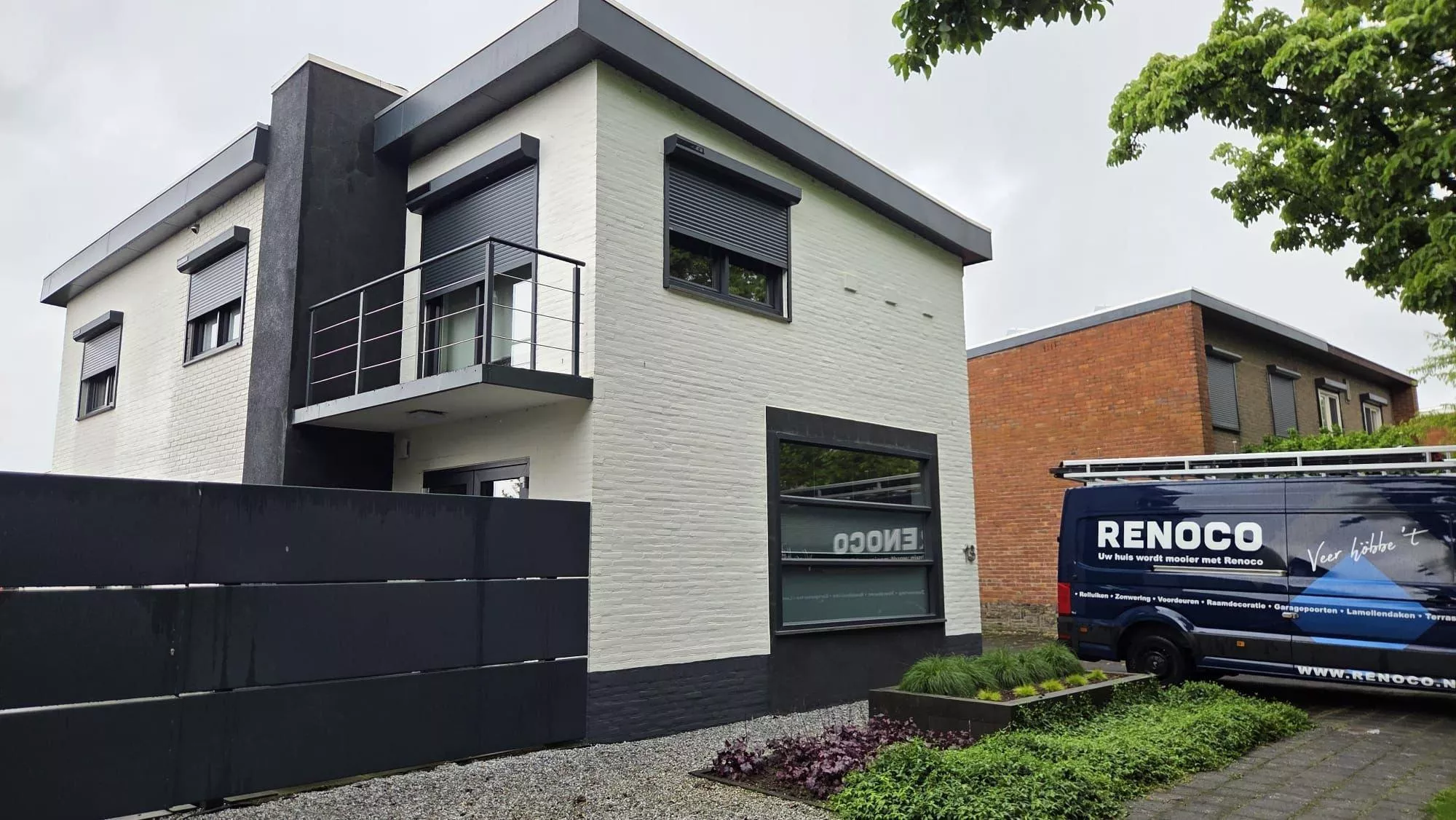 Modern house with black roller shutters by Renoco and the service van on site