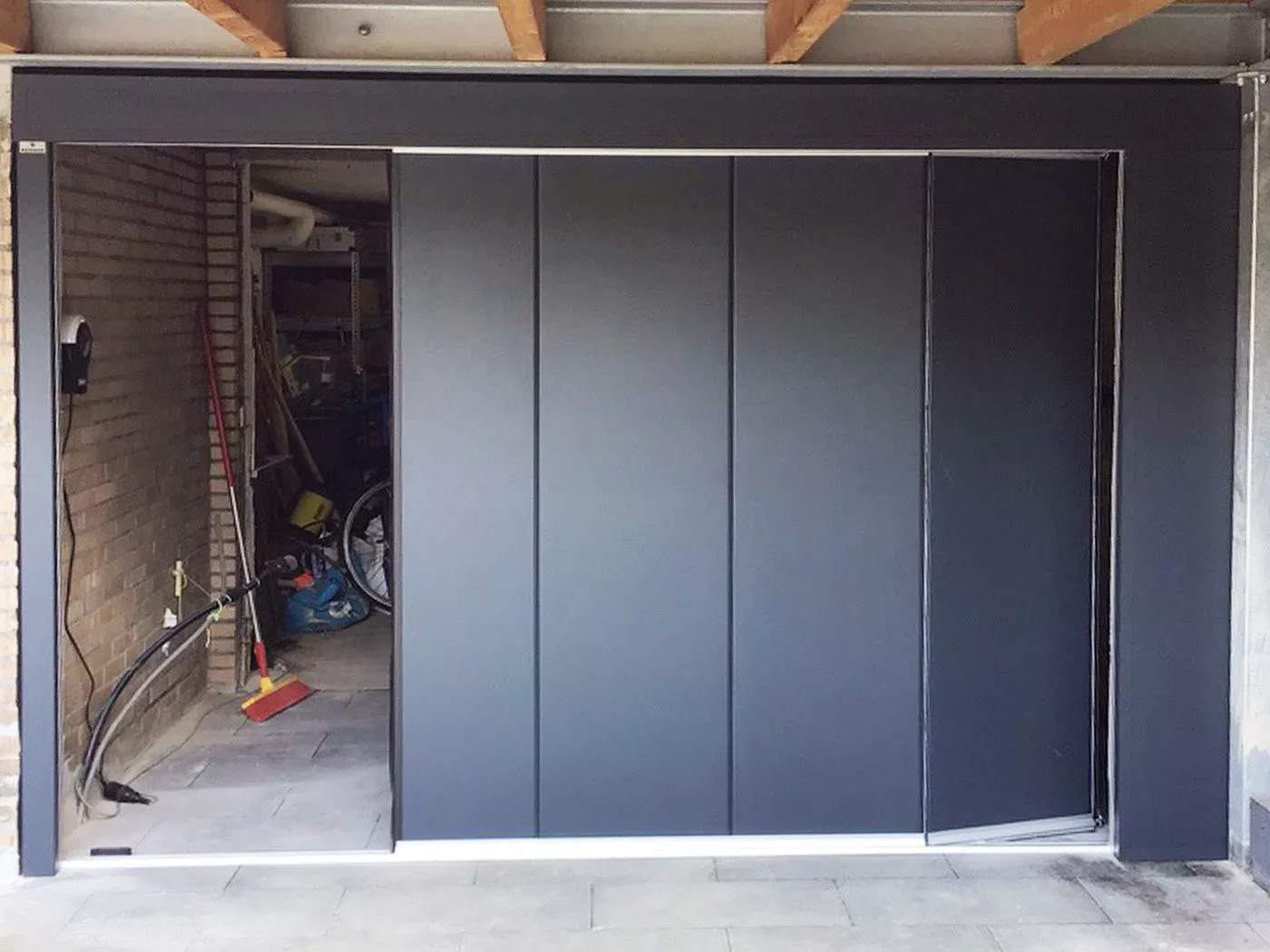 Black side-sliding sectional door with a sleek finish in a garage setting.